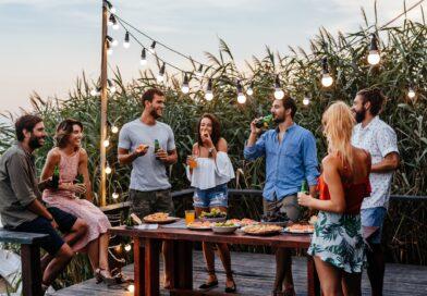 Freunde genießen Essen und Getränke im Garten unter Lichterkette | Terrassenüberdachung