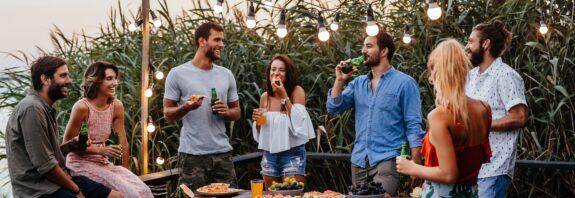 Freunde genießen Essen und Getränke im Garten unter Lichterkette | Terrassenüberdachung